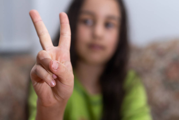 gesture and happy people concept - smiling little girl in blank t-shirt showing peace gesture with fingers. - Foto, imagen