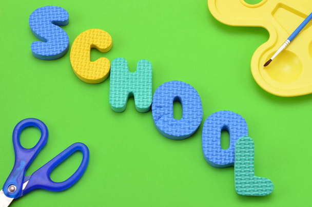 the word school from the letters of the children's alphabet close-up on a green background - Φωτογραφία, εικόνα