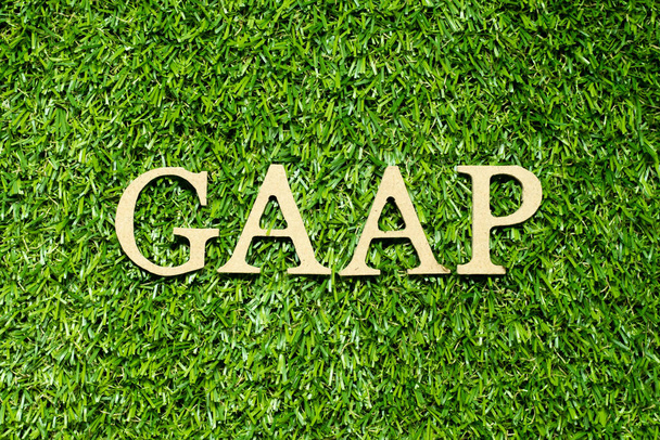 Wood alphabet letter in word GAAP (Abbreviation of Generally accepted accounting principles) on green grass background - Fotografie, Obrázek