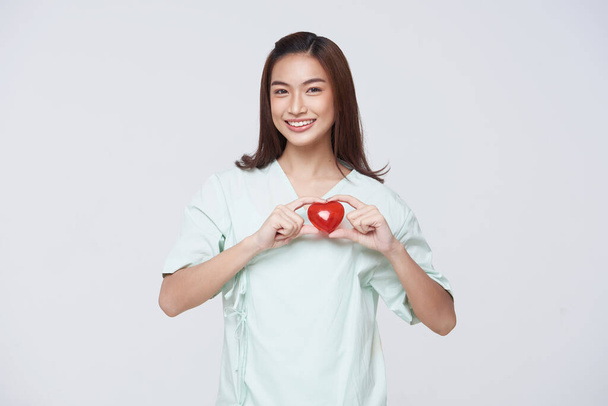 Happy asian woman patient showing heart isolated on white background. Insurance cardiovascular and cardiac concept. - Foto, Imagem