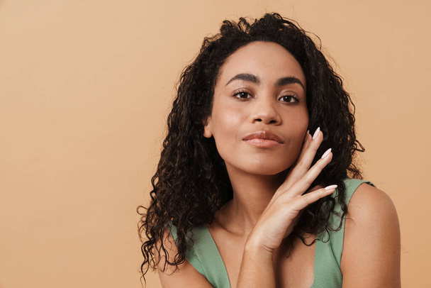 Young black woman touching her face and looking at camera isolated over beige background - Photo, Image