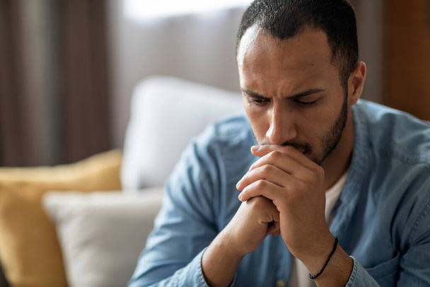 Closeup Portrait Of Thoughtful Young Black Man At Home Interior, Depressed Pensive African American Guy Resting Chin On Hands And Looking Away, Suffering Mental Breakdown Or Seasonal Depression - 写真・画像