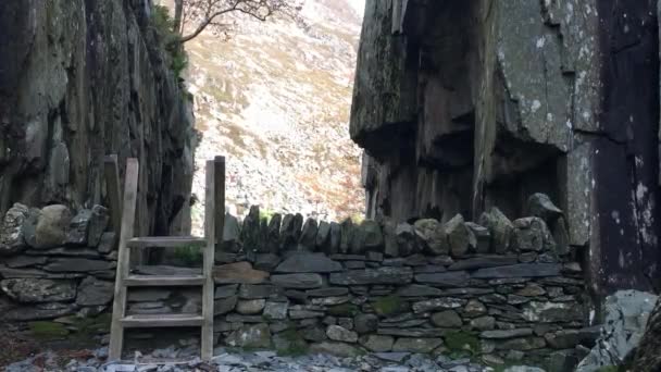 A plus-sized woman climbs a ladder stile over a dry stone wall leading into a narrow gorge on a hiking trail in Snowdonia National Park. Llyn Idwal, North Wales, UK - Séquence, vidéo