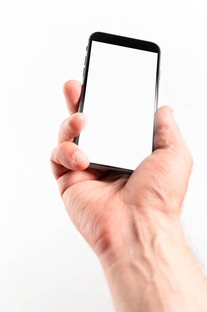 Man hand using smartphone on white background. Closeup shot of man hand holding a smartphone. Vertical image - Foto, Imagen