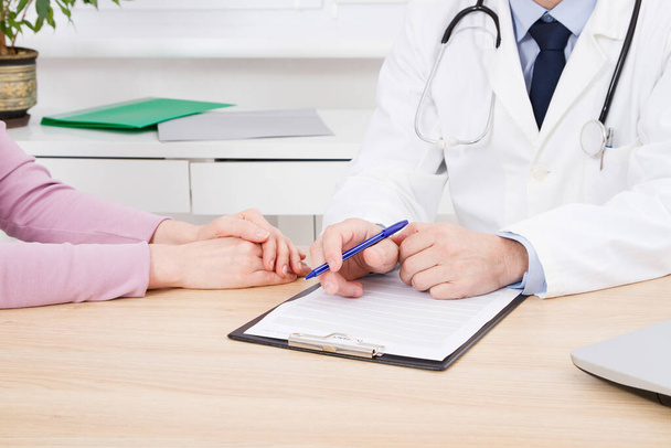 Arzt und Patient diskutieren über etwas, Hände am Tisch, Krankenversicherung. - Foto, Bild