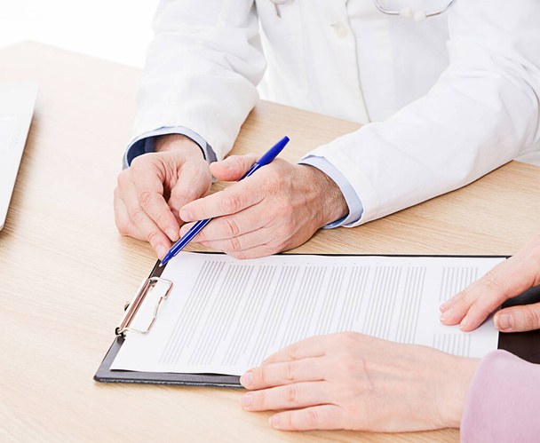 Docteur et patient discutent de quelque chose, juste les mains à la table, assurance médicale. - Photo, image