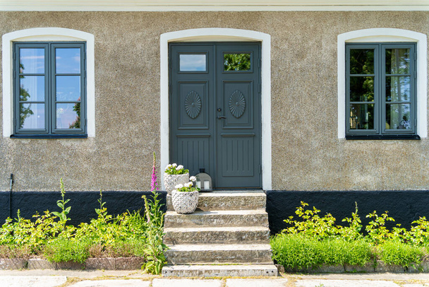 Image of Closed green wooden entrance door with stone stairs and concrete walls of the scandinavian style house - Photo, Image