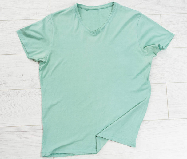 Groen t-shirt close-up bovenaanzicht op houten achtergrond, t-shirt kopieerruimte - Foto, afbeelding