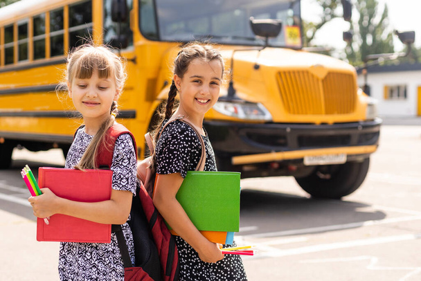 Εκπαίδευση: Χαμογελώντας μαθητές Φίλοι έτοιμοι για το σχολείο δίπλα στο σχολικό λεωφορείο. - Φωτογραφία, εικόνα