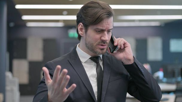 Retrato de un joven hombre de negocios hablando enojado en el teléfono inteligente - Foto, imagen