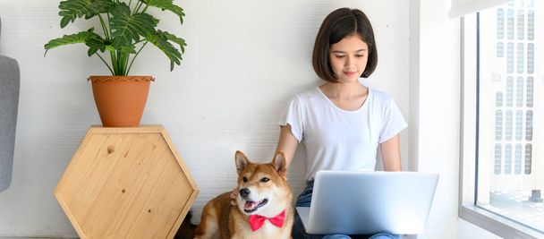 Красива молода азіатка працює на підлозі в вітальні зі своїм японським собакою Шіба Іну, Весела і гарна пара з людьми і домашнім улюбленцем. - Фото, зображення