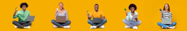 Happy millennial international women and men sitting with laptop, showing credit card, shopping online, isolated on yellow background, studio, panorama. Modern technology for sale, money and finance - Photo, Image