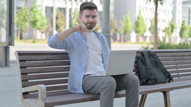 Thumbs Down by Man with Laptop Sitting on Bench - 写真・画像