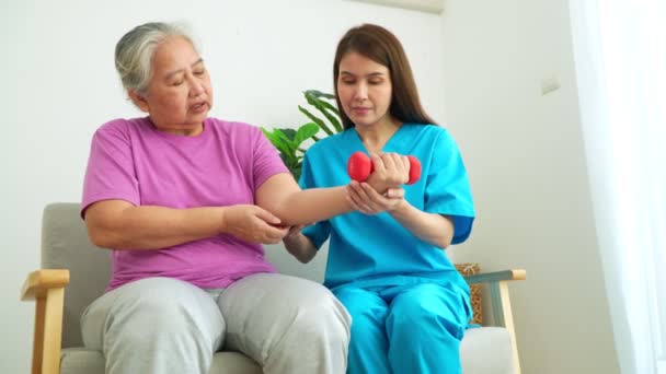 Asian Caregiver nurse doing physical therapy assistance and support teach body and muscle exercises to elderly women. Physical therapy and senior citizens rehabilitation concept. - Video, Çekim