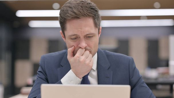 Empresario de mediana edad reaccionando a la pérdida mientras usa el ordenador portátil - Foto, imagen