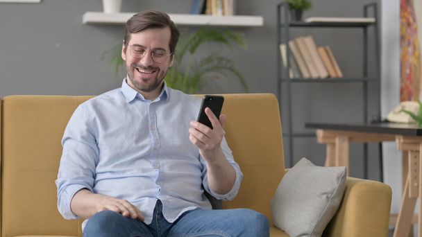 Beard Young Man having Success on Smartphone at home - Photo, Image