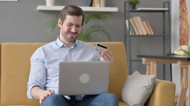 Beard Young Man with Unsuccessful Online Payment on Laptop on Sofa - Photo, Image