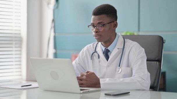 アフリカの医師がオフィスのノートパソコンでビデオ通話で話す - 写真・画像