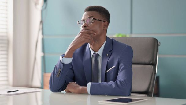 オフィスに座っている間に考えるアフリカのビジネスマン - 写真・画像