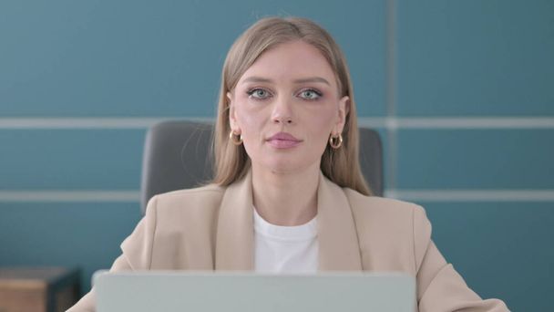 Close Up of Young Businesswoman Looking at Camera while using Laptop in Office - Fotoğraf, Görsel