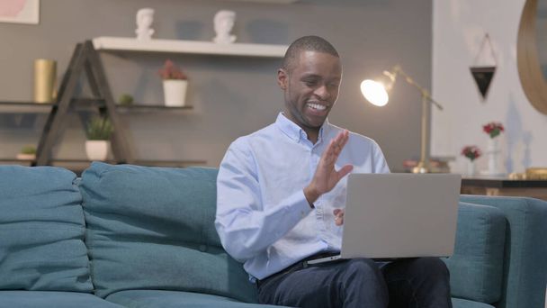 The Young African Man Talking on Video Call on Laptop on Sofa - Foto, immagini