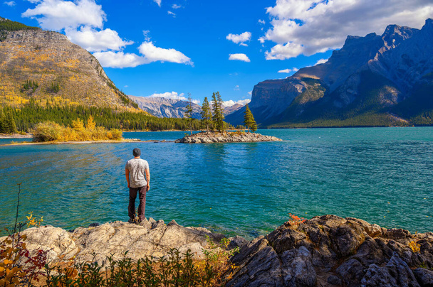 Young hiker standing at Lake Minnewanka in Banff National Park, Canada. Minnewanka is a glacial lake and the 2nd longest lake in the mountain parks of the Canadian Rockies. - Φωτογραφία, εικόνα