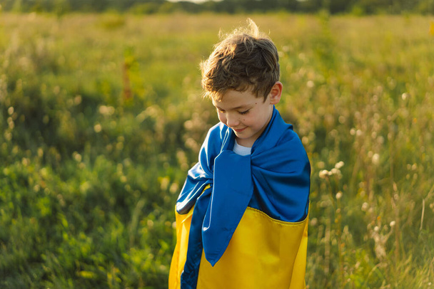 Ukraines Independence Day. Ukrainian child boy in white t shirt with yellow and blue flag of Ukraine in field. Flag of Ukraine. Constitution day. Stand with Ukraine and Save - Fotografie, Obrázek