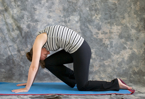 vrouw doen yoga houding marjaryasana variatie of sterke kat po - Foto, afbeelding