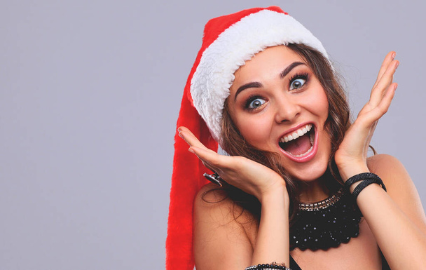 Attractive smiling woman in Santa Cap. Isolated over a gray - Фото, зображення