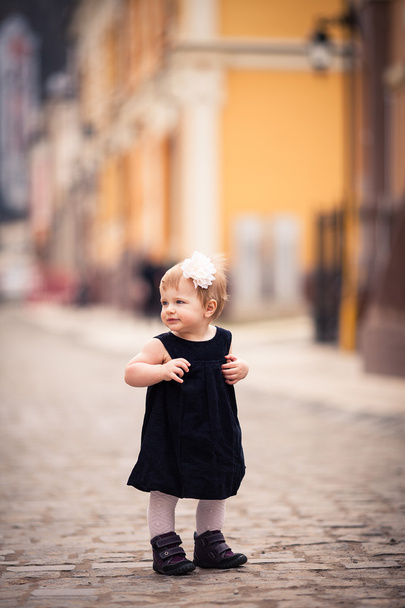 A little baby girl stands on the street - Photo, Image