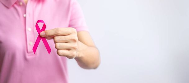 Рожевий жовтень місяць обізнаності про рак молочної залози, жіноча рука тримає рожеву стрічку і носить сорочку для підтримки життя і хвороб людей. Національний місяць виживання раку, концепція Дня матері та Всесвітнього раку
 - Фото, зображення