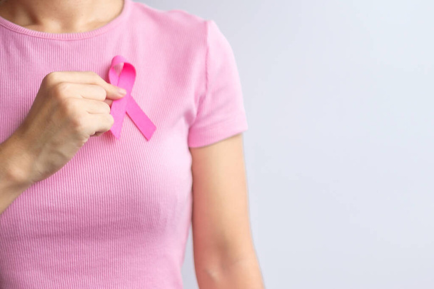 Розовый октябрь месяц рака молочной железы осведомленности, женщина держит в руках розовую ленту и носить рубашку для поддержки людей жизни и болезни. Национальный месяц переживших рак, концепция Всемирного дня борьбы с раком - Фото, изображение