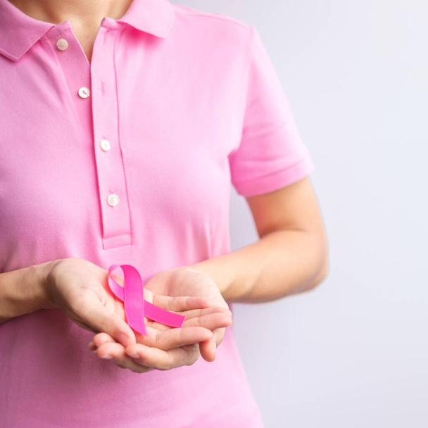 Pink October Breast Cancer Awareness month, woman hand hold pink Ribbon and wear shirt for support people life and illness. National cancer survivors month, Mother and World cancer day concept - Photo, image