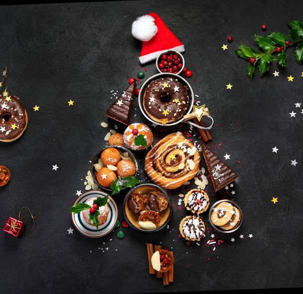 Christmas tree with sweets and cookies decoration on dark background. Holiday food. Top view, copy space - Valokuva, kuva