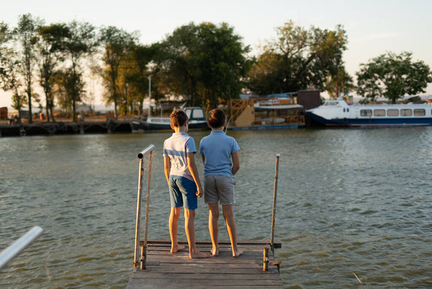 Два хлопчики рибалять на заході сонця на озері. Літнє хобі та концепція дозвілля
 - Фото, зображення