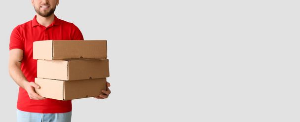 Delivery man holding parcels on light background with space for text - Фото, зображення