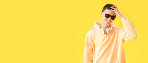 Teenage boy with headphones on yellow background with space for text - Foto, imagen