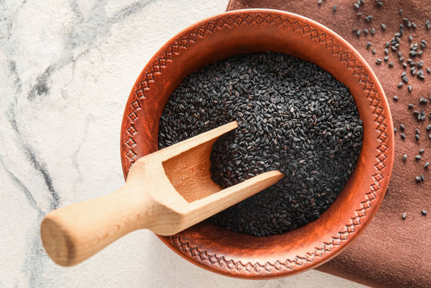Bowl and scoop of black sesame seeds on light background, closeup - Foto, Imagem