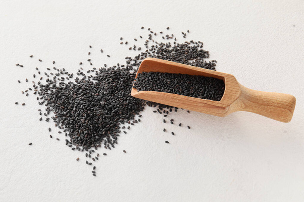 Wooden scoop with black sesame seeds on light background - Zdjęcie, obraz