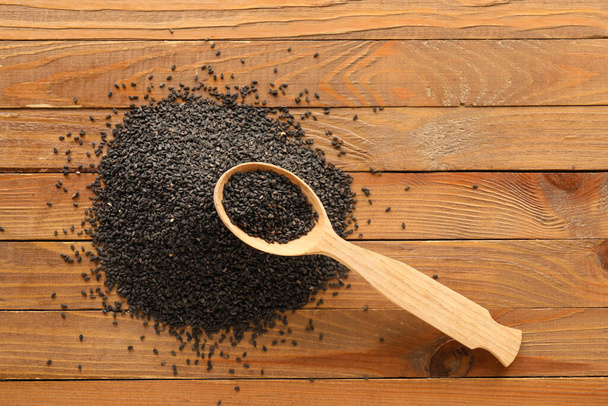 Spoon of black sesame seeds on wooden table - Φωτογραφία, εικόνα