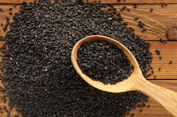 Spoon of black sesame seeds on wooden table, closeup - Zdjęcie, obraz
