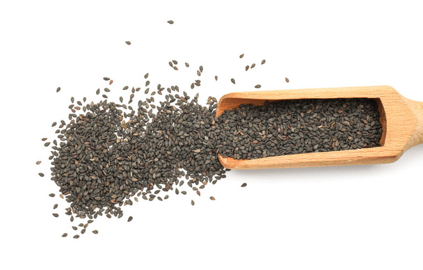 Wooden scoop with black sesame seeds on white background, closeup - Zdjęcie, obraz