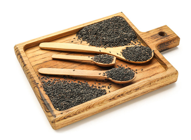 Wooden board with spoons of black sesame seeds isolated on white background - Foto, imagen