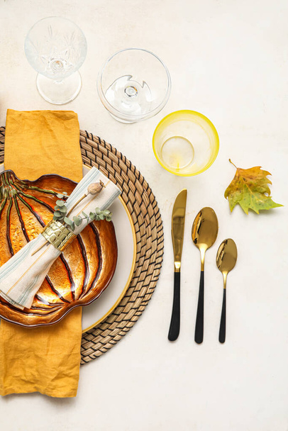 Stylish table setting with autumn decor and pumpkin shaped plate on light background - Photo, image