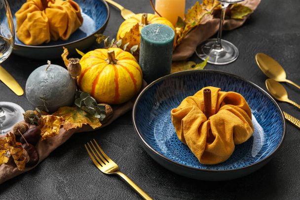 Beautiful table setting with pumpkins and candles on dark background, closeup - Foto, immagini