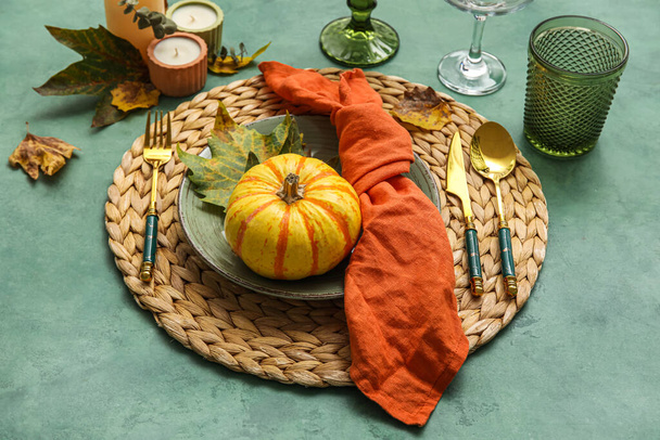 Beautiful table setting with autumn decor and pumpkin on green background - Foto, Bild