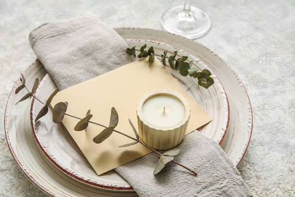 Dinnerware with blank card, eucalyptus branches and candle on grey table - Zdjęcie, obraz