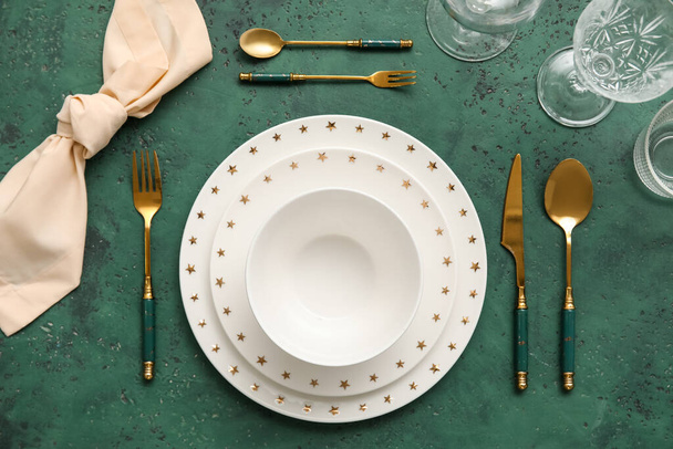 Elegant table setting with plates, cutlery and glasses on green background - Photo, image