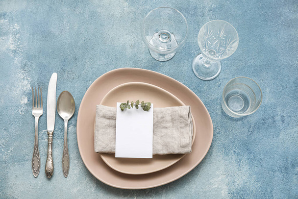 Elegant table setting with blank card and eucalyptus branch on blue background - Φωτογραφία, εικόνα