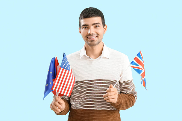Young man with different flags on blue background - Photo, Image